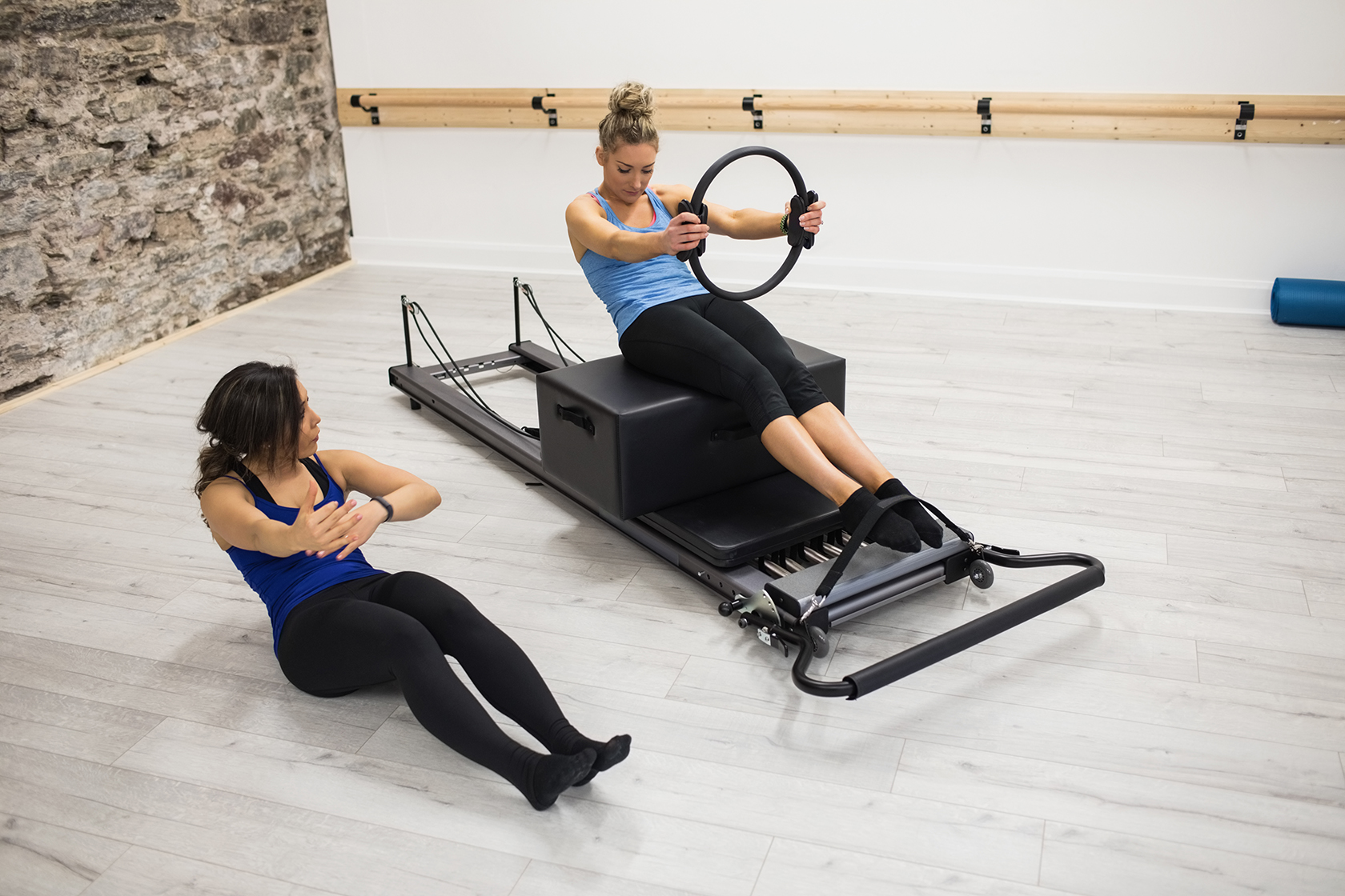 Insegnante Pilates spiega esercizio con il magic circle a cliente sul reformer